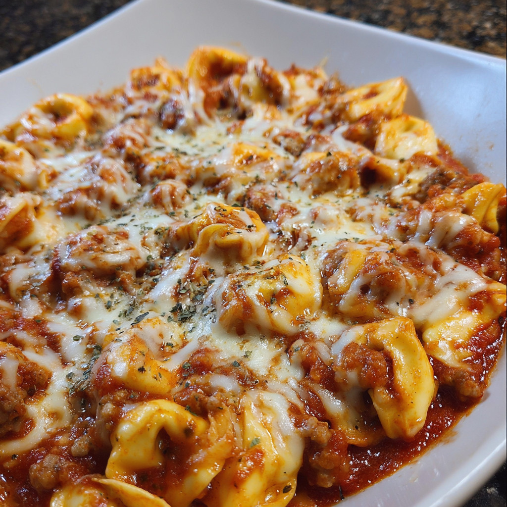 Eine Sch&uuml;ssel mit Cheesy Sausage Tortellini, die in einer Sauce serviert werden.