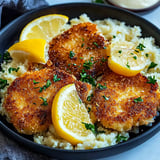 Auf dem Teller liegt Schweineschnitzel, garniert mit Zitronenecken.