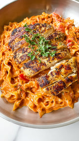 Ein Bild von Chicken Rosé Pasta (Pink Pasta), das eine Kombination aus gekochtem Hühnchen, Pasta und Tomaten enthält.