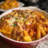 Ein Baked Ziti mit italienischer Sausage in einem weißen Teller.